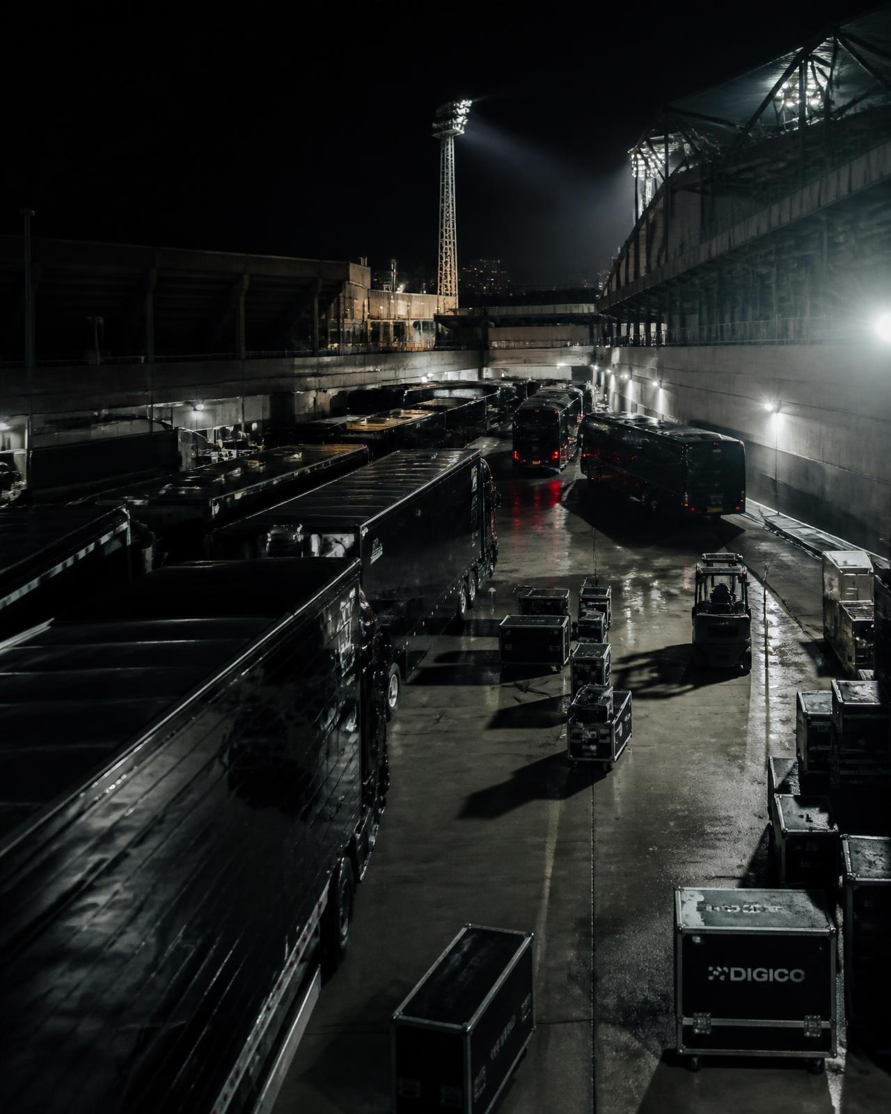Tour buses and equipment trucks at a stadium